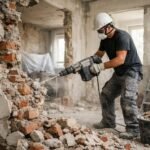Férfi falbontás közben, romos szobában, építkezési munkálatok.
